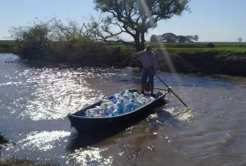 Barqueiro leva água para famílias atingidas pela enchente em Camaquã. Foto: Divulgação.